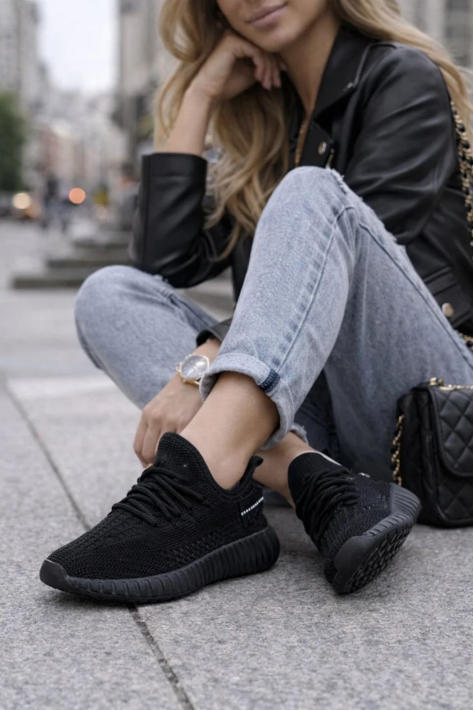 Woman wearing evening black trainers with a leather jacket and jeans