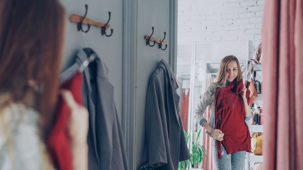 Woman checking the fit of an outfit in a boutique mirror while learning how to dress her body shape