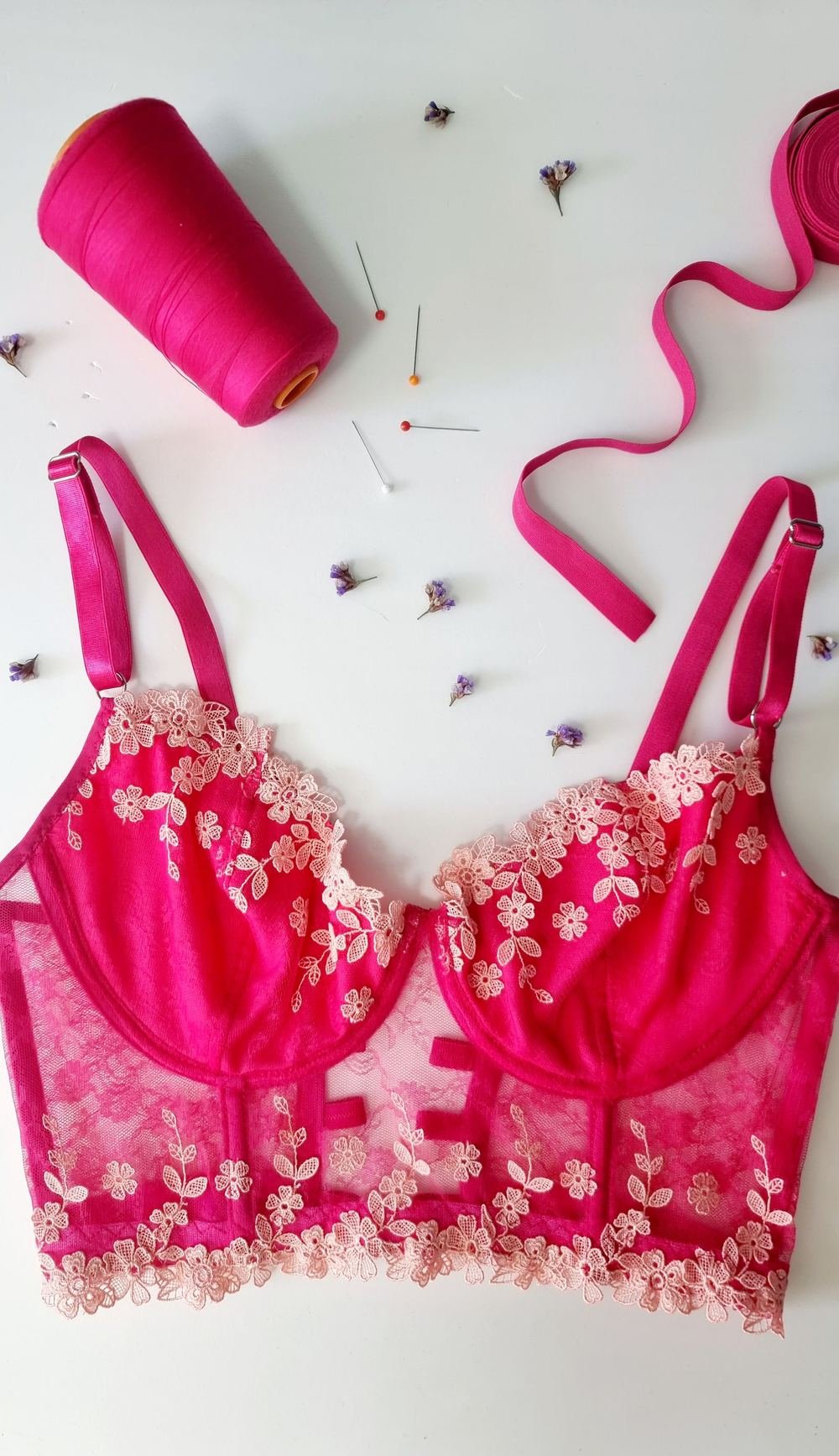 Lace bra flat lay with sewing thread and pins, illustrating how to measure bra size at home