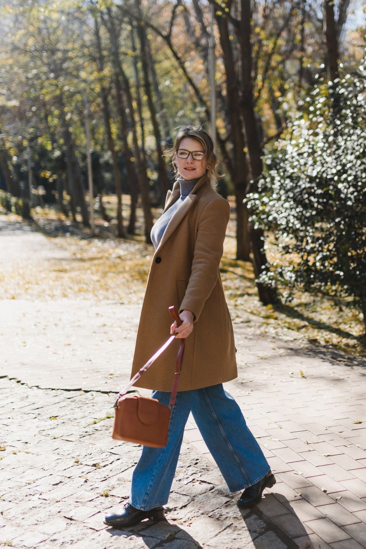 Woman in a camel coat with straight jeans and ankle boots
