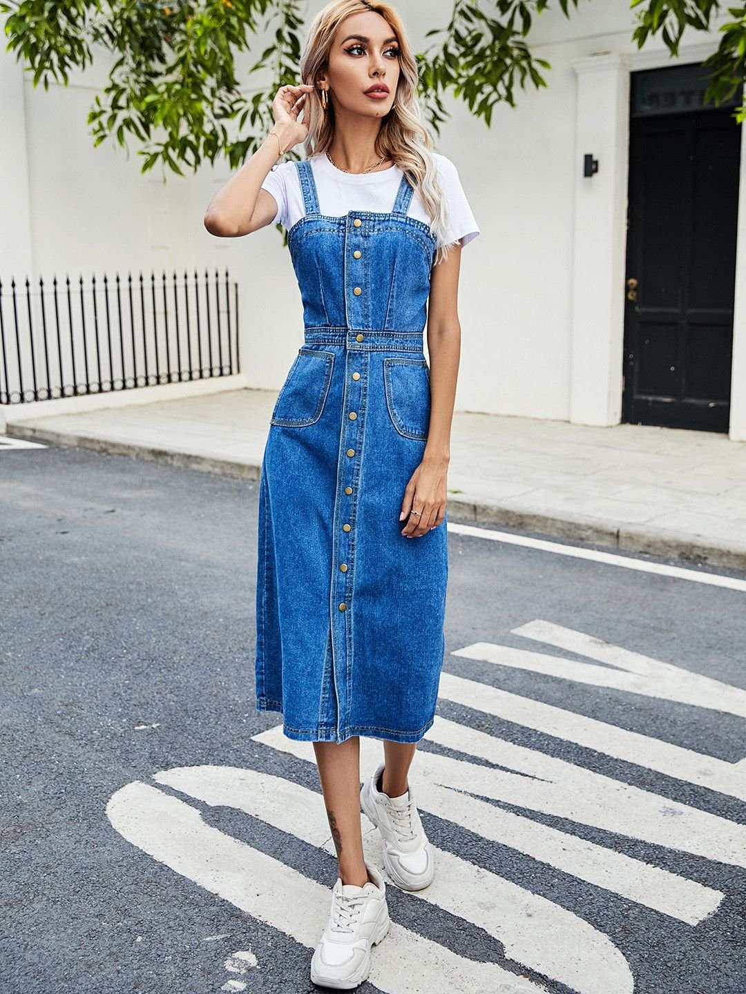Woman wearing an evening denim pinafore dress over a white T-shirt