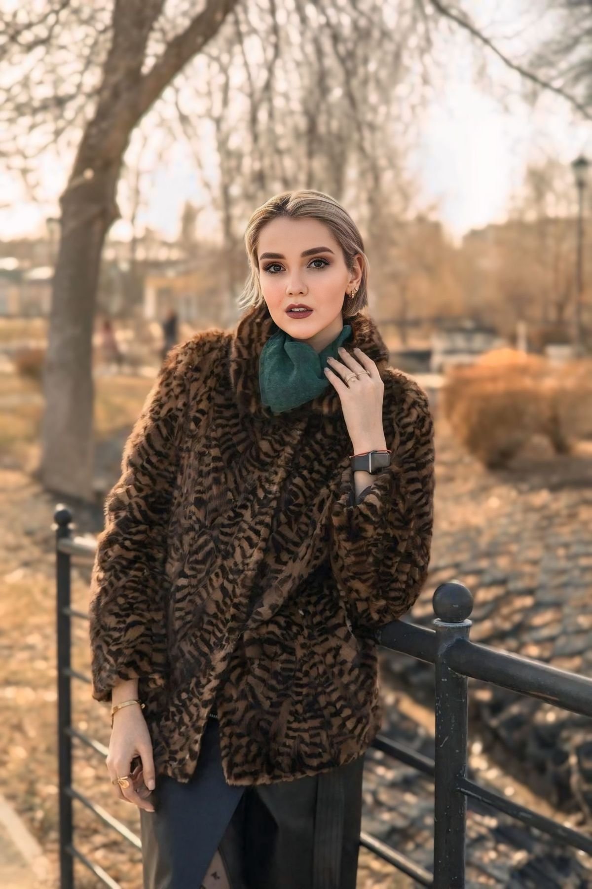 Woman in a fur coat posing outdoors in a city park