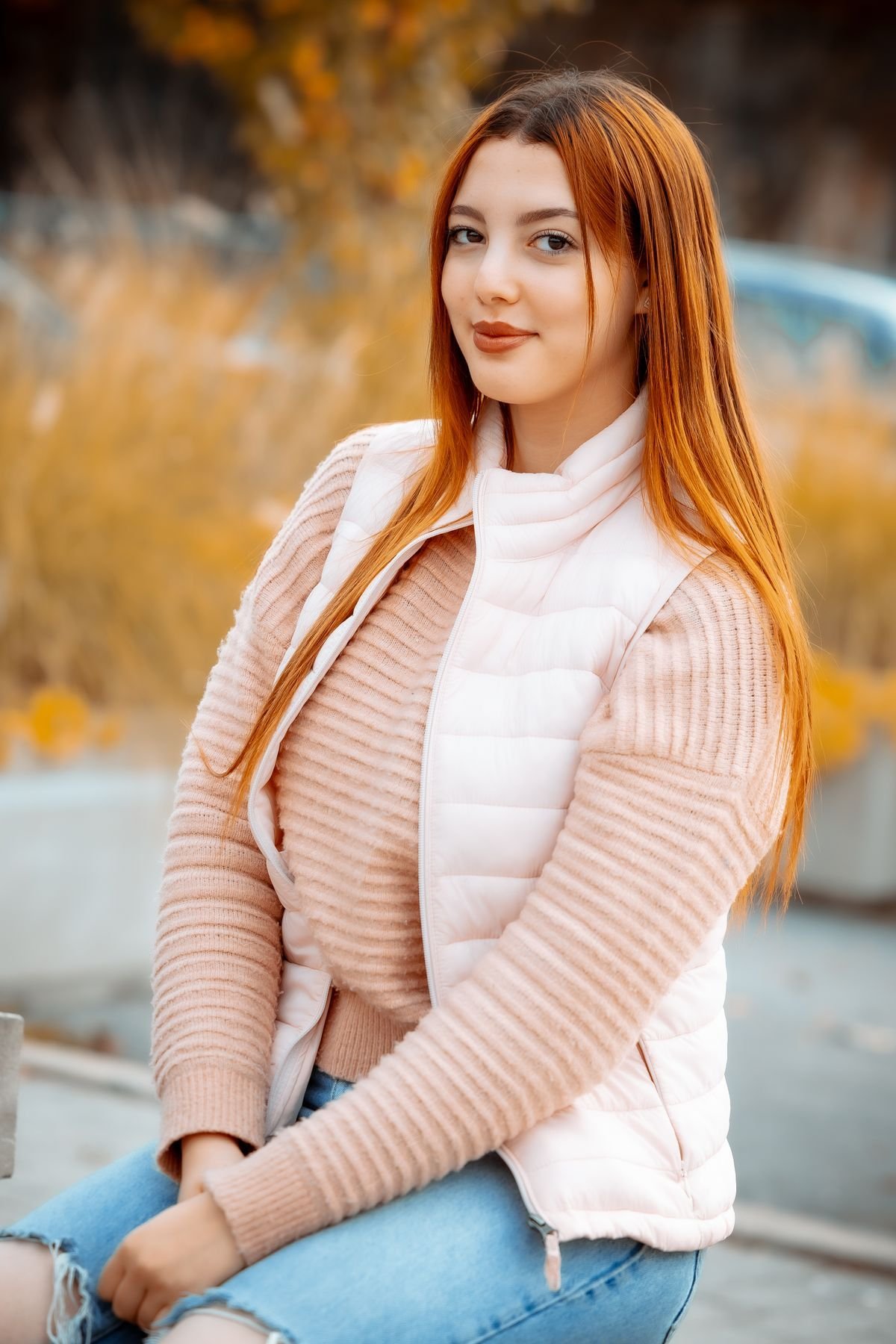 Woman in a pale pink puffer gilet over a blush knit and jeans