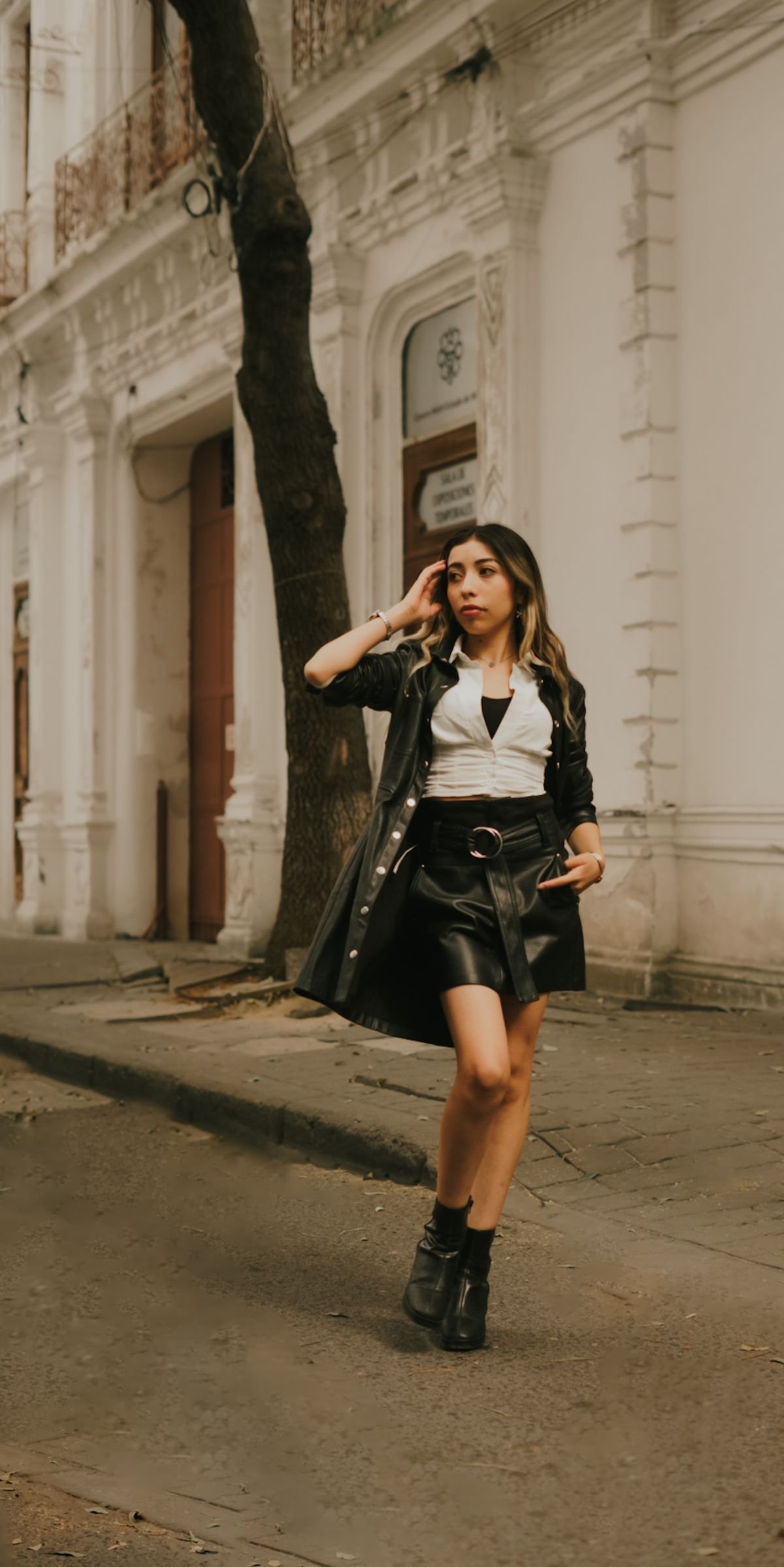 Woman in a black leather skirt and jacket walking on a city street