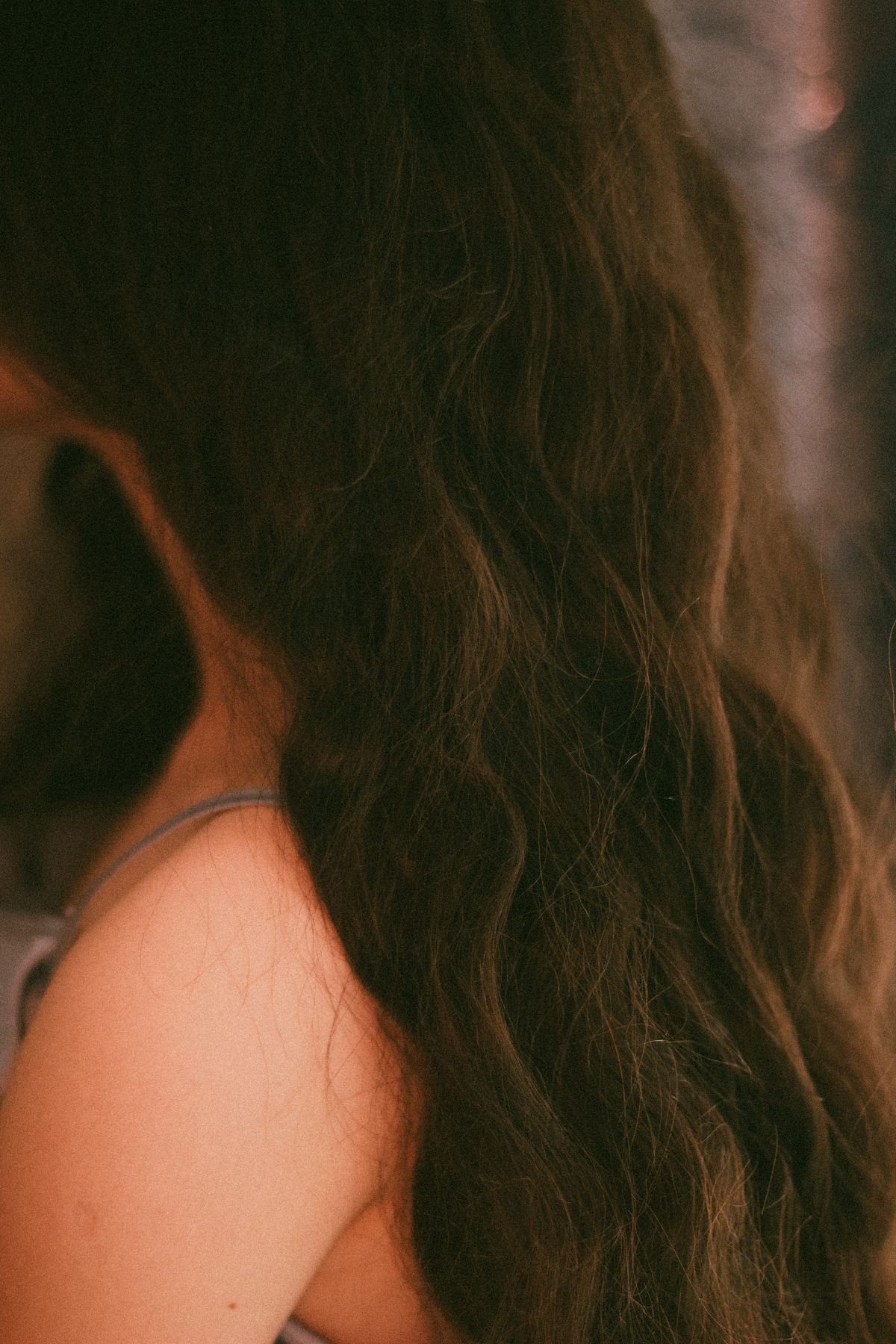 Vertical close-up of a woman with long dark hair in natural light