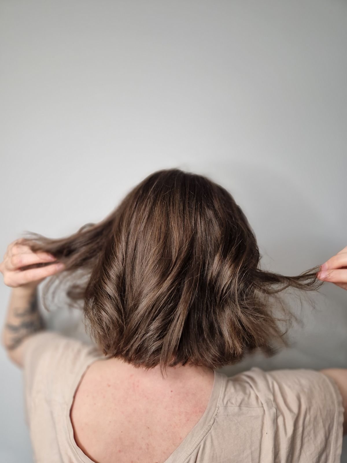 Woman with short brown hair against a plain grey background