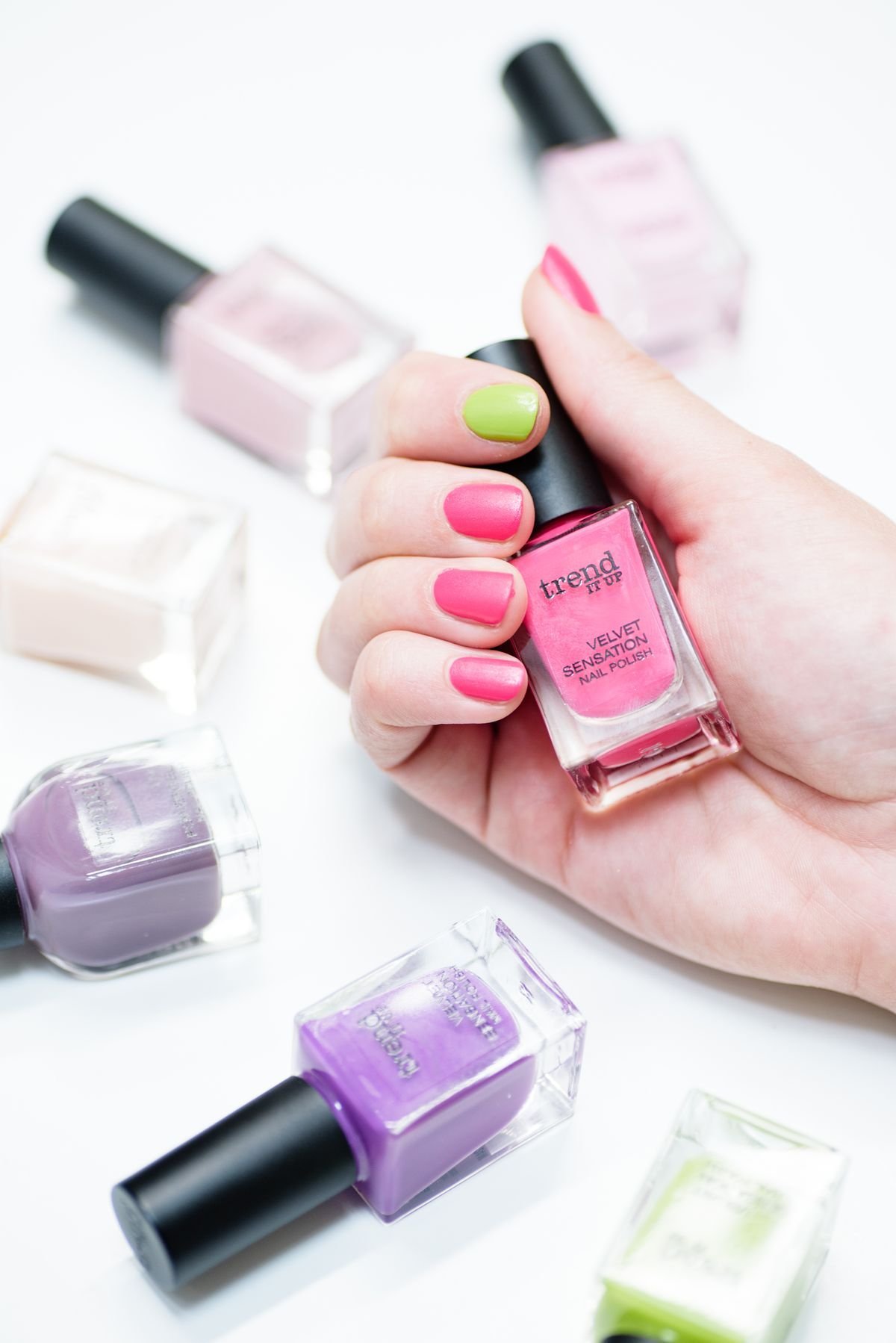 Hand holding nail polish bottles in vibrant colours