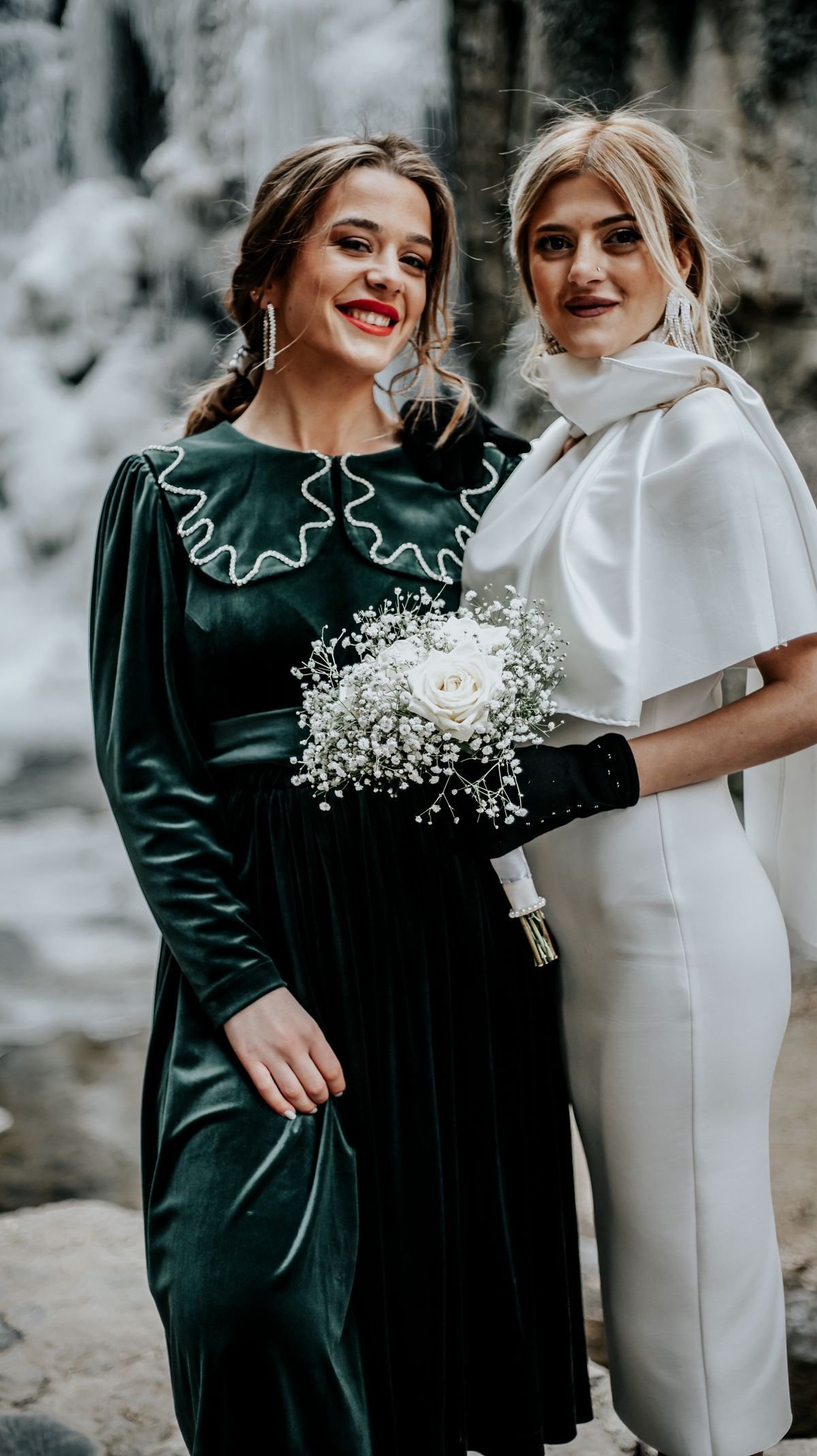 Two elegant women posing with a bouquet at a wedding