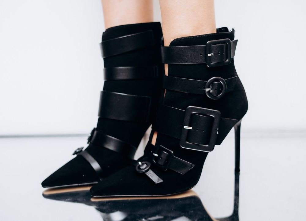 Black heeled boots on a reflective surface showing why correct shoe size conversion matters for boot fit